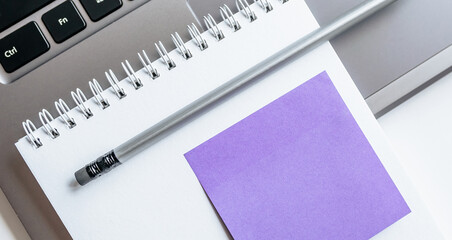 Notebook, laptop, stickers, paper clips in the workspace on the table in the office.