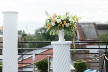 Columns, statues and bouquets of flowers in front of the wedding arch