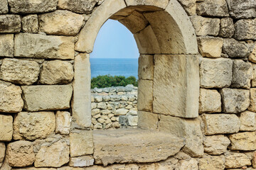 Fototapeta na wymiar View from the window. Ancient stone wall with a window and a view of the sea.
