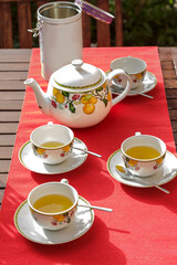 Teiera con tazzine di tè sopra una tovaglia rossa in un tavolo di legno