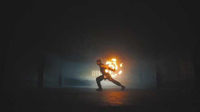 Fire show artist in the dark building.