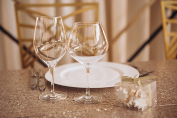 Table setting for a wedding party. a round table with a white tablecloth, glasses, white plates in the rays of the setting sun.