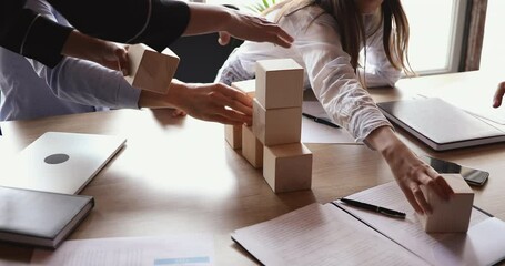 Team people partners building tower of wooden blocks on office table together developing strategy for business growth in group teamwork. Successful professional management concept. Close up view.