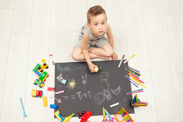 Little child sitting alone using chalk painting on black paper