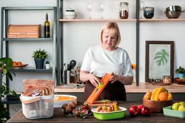Blond female standing by kitchen table with variety of fresh fruits