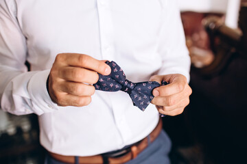 stylish groomsmen helping happy groom getting ready in the morning for wedding ceremony. luxury man in suit in room. wedding day.