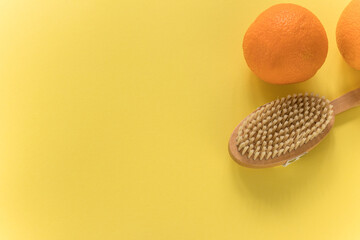 Body brush and big oranges for anti-cellulite massage on yellow background. Lay out design with copy space. Cactus exfoliating brush for body care