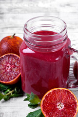 Smoothie with blood orange juice in the mason jar on the white wooden table