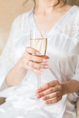 bride's hand with beautiful manicure and engagement ring and champagne