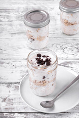 Overnight oats with yogurt topped with chocolate chips on the white wooden table