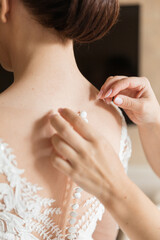 Fototapeta premium Bride`s dress. White dress of the bride who help to button up girlfriends. the bride admires the dress