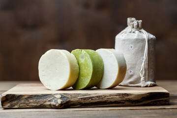 Natural handmade round soap bars with different ingredients on a brown wooden background