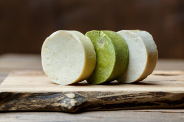 Natural handmade round soap bars with different ingredients on a brown wooden background