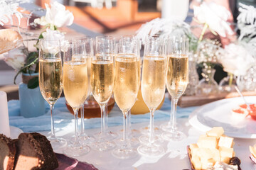 Glasses of chilled champagne stand on a table with a tablecloth for a welcome treat for guests of the event