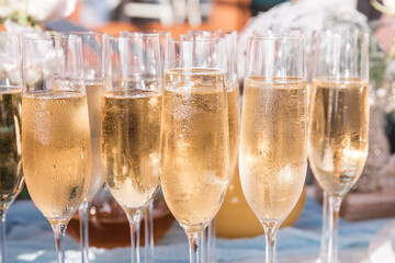 Glasses of chilled champagne stand on a table with a tablecloth for a welcome treat for guests of the event