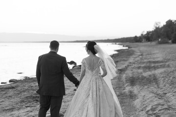 Newly married couple walking away together on the beach