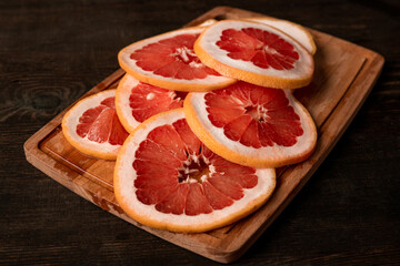 Pile of sliced fresh grapefruit on wooden board ready to be put in fruit dryer