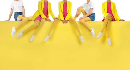 Women wearing yellow tights and stylish shoes sitting on color background, closeup
