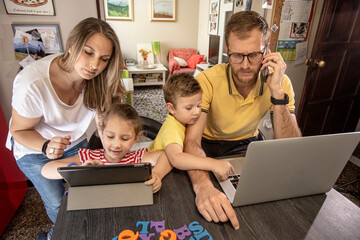 famiglia felice gioca con il tablet mentre il papa lavora al computer in  modalità smart working