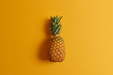 Ripe pineapple isolated on yellow background. Exotic fruit low in calories, loaded with nutrients...
