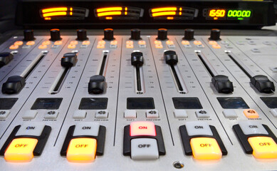 Buttons, volume levels, switches on the audio mixer control panel working on a table at the radio...