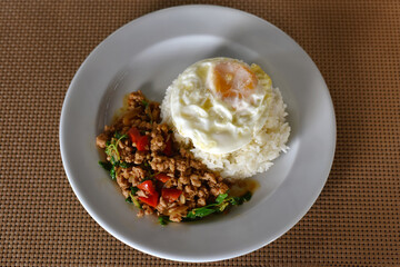 Thai Food, Rice topped stir-fried chicken and basil with Fried egg on white plate. is popular menu of Thailand street food that has a strong spicy flavor and it is a very delicious. Top view