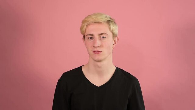 the guy is chewing, smiles and twists his head, blonde hair, long neck, pink background, Young man