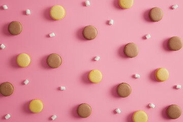 Dessert, confectionery, eating, calories concept. Two colored french yummy macaroons with marshmallow isolated on pink background. Sweet tasty cookies. Cake macaron. Creative layout. Junk food
