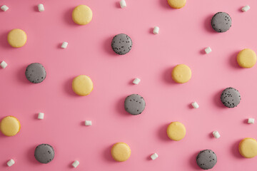 Colorful tasty french macaroons with white appetizing marshmallow isolated on pink studio background. Traditional delicious cakes. Gourmet confectionery products. Junk food, calories, temptation