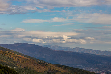 Sky with beautiful puffy white clouds and picturesque mountains, late autumn day in Northern Greece, Xanthi region, high angle colorful naturalistic view
