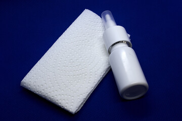 Plastic white bottle with nose drops napkin on blue background.The concept of colds, flu and runny nose