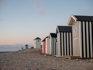 Tiny striped beach huts at sunset