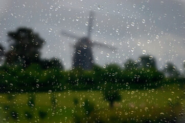 Krople deszczu na szybie i wiatrak w Holandii