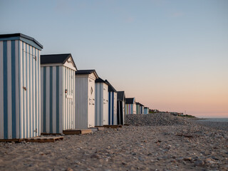 Obraz na płótnie Canvas Row of tiny striped beach huts in golden evening light