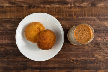 Top view typical colombian almojabanas, traditional colombian cheese bread over white plate with oat drink on wood background. Traditional bakery