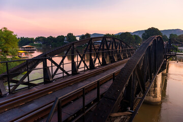 Fototapeta na wymiar River Kwai bridge with twilight sky at dawn in Kanchanaburi, Thailand. Beautiful view of Railway in early morning. Tourist famous landmark of historic world war2. travel after covid-19 lockdown.