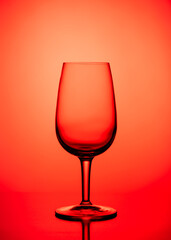 One Empty wine glass isolated on red background.