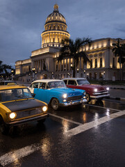 Fototapeta na wymiar Old car on streets of Havana with Capitolio building in background with reflection on rain time. Cuba