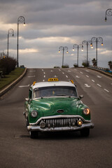 Old car on Malecon street of Havana with storm clouds in background. Cuba