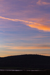 Purple-magenta clouds. Landscape with bloody  dawn. The terrain in southern Europe.  Panorama. Mirror lake with a reflection of nature. Morning silence. Water surface.