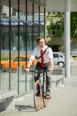 Contemporary young businessman riding bicycle on sunny summer day