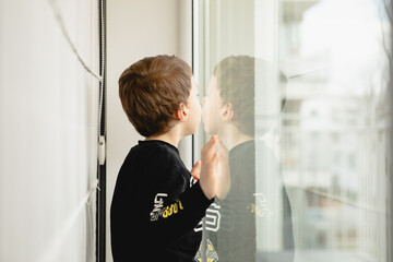 little boy looking through the window inside the house  © sandrqa