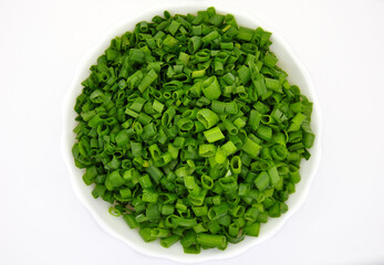 chopped green onions in a white plate on a white background view from the top