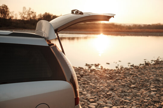 Open Car Trunk against the River at Sunset
