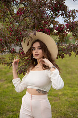 Long-haired girl in a hat in an Apple orchard in spring