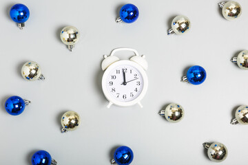  Pattern of white alarm clock, blue and silver Christmas balls on a gray background. Christmas or New Year celebration concept. top view, flat lay
