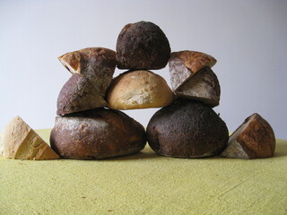 pedazos de pan de distintos tipos cortados en cuñas apiladas formando una torre, distintas harinas, de espelta blanca, centeno, trigo. Vista frontal
