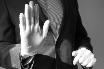Man's hand in the glove and in a business-like suit shows a stop sign. Keep a distance. The...