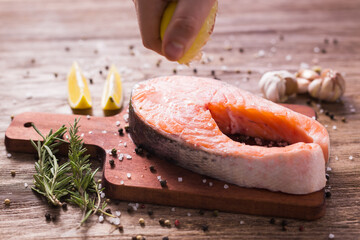 Squeezing fresh lemon juice on the fillets of fish. Cooking salmon steak.