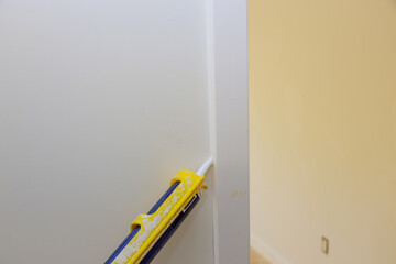 Worker hands applying filling silicone for sealing in corner wall door molding trim